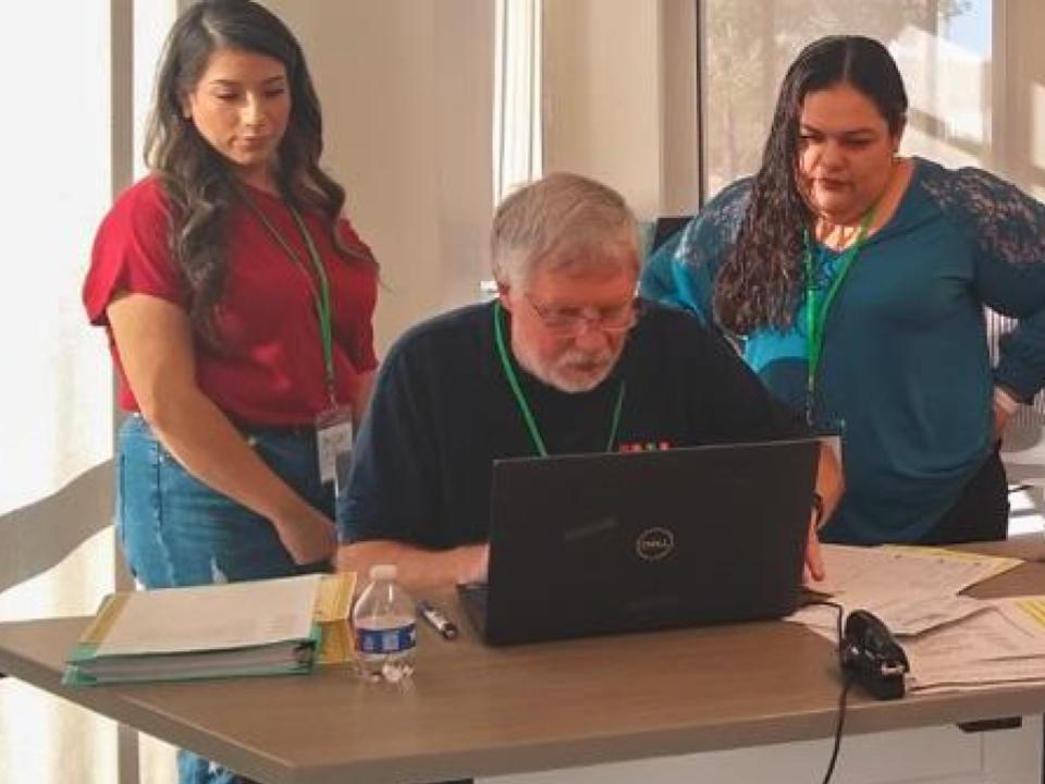 Faculty member and students at a computer screen.